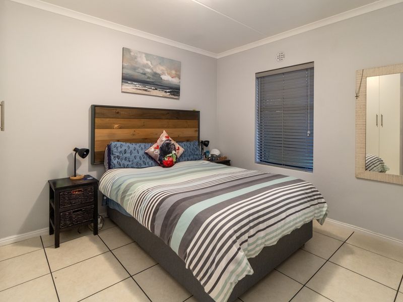 A well-maintained bedroom featuring tiled flooring, a built-in wardrobe, and venetian blinds, offering a clean and functional living space.