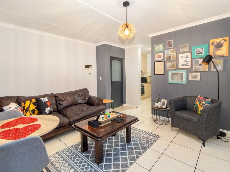 Open-plan living area featuring tiled flooring, a modern pendant light, and a view through to the kitchen area.