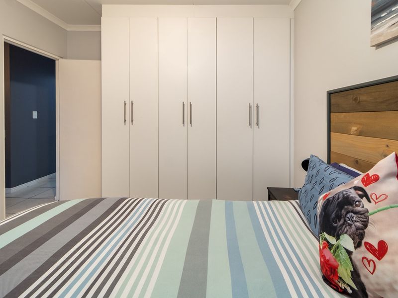 A well-maintained bedroom featuring floor-to-ceiling built-in cupboards with modern handles and decorative coving.