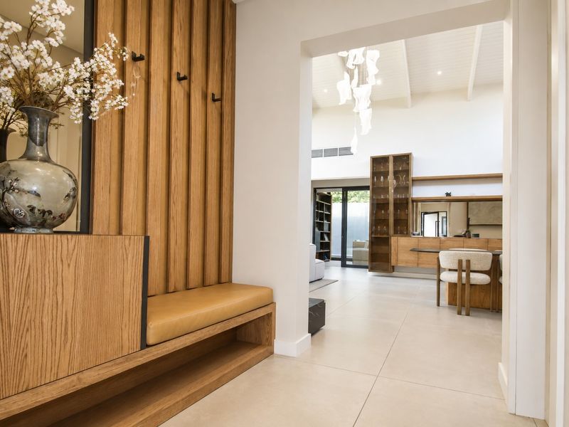 Elegant entrance hallway featuring custom timber wall paneling with integrated bench seating, leading into a bright, open-plan living area with vaulted ceilings.