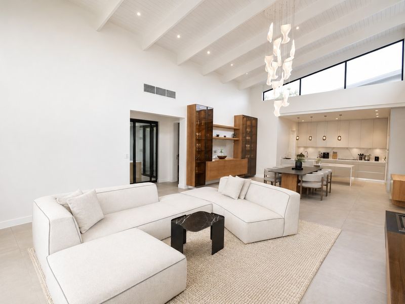 Spacious open-plan living and kitchen area featuring high vaulted ceilings with exposed beams, modern cabinetry, and premium finishes throughout.