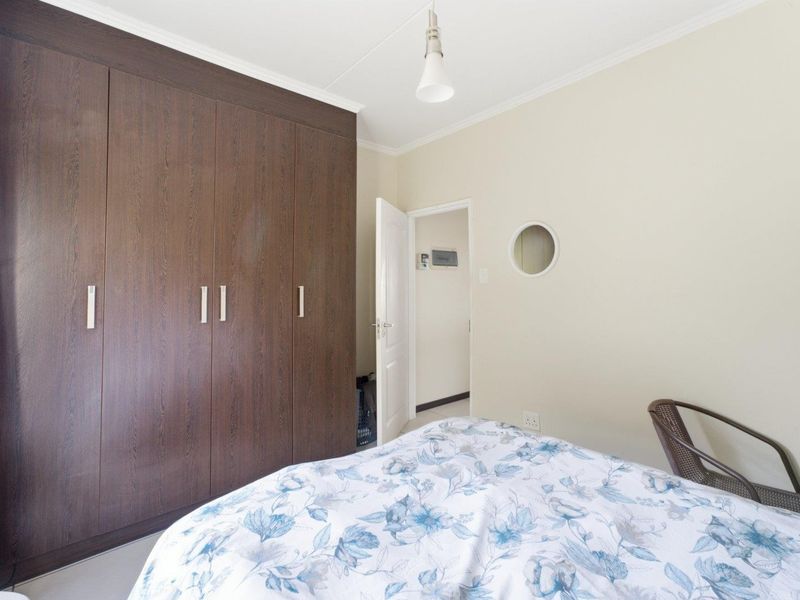A bedroom featuring dark wood built-in cupboards, a unique circular window, and neutral wall finishes.