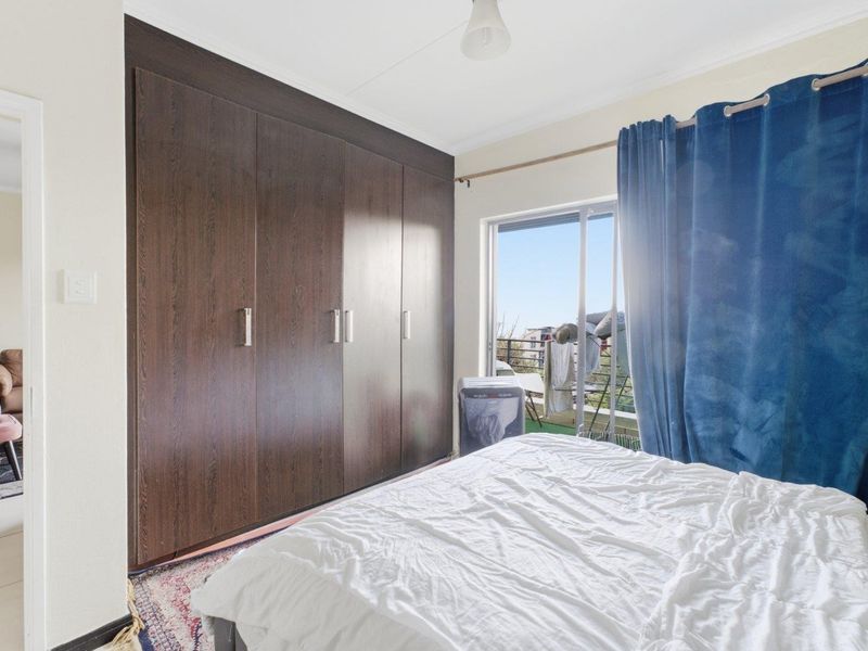 Bedroom featuring dark wood built-in cupboards and a sliding glass door providing access to an outdoor balcony area.
