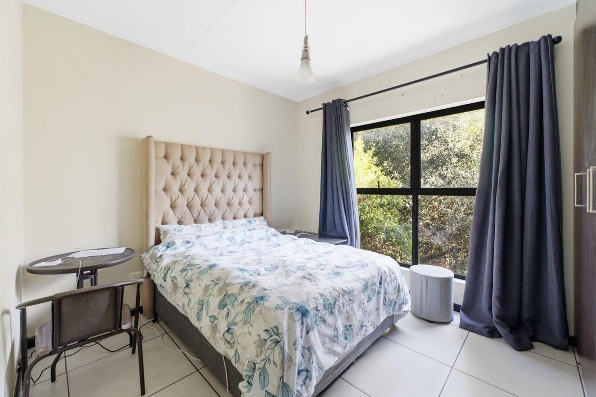 A bedroom featuring tiled flooring, a large window with natural light, and built-in cupboard storage.