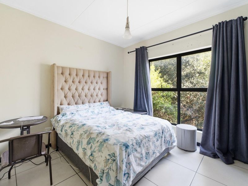 A bedroom featuring tiled flooring, a large window with natural light, and built-in cupboard storage.