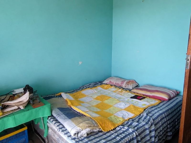 A bedroom featuring tiled flooring and a wooden door, currently requiring cosmetic updates to the wall finishes.