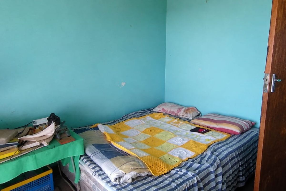 A bedroom featuring tiled flooring and a wooden door, currently requiring cosmetic updates to the wall finishes.