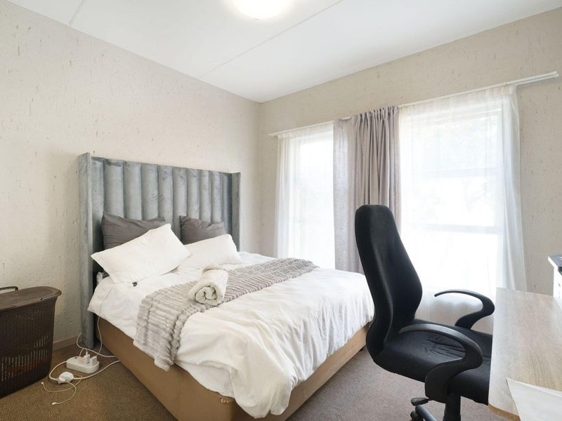 A functional bedroom featuring carpeted flooring and large windows with curtain tracks, providing natural light and a neutral base for interior design.