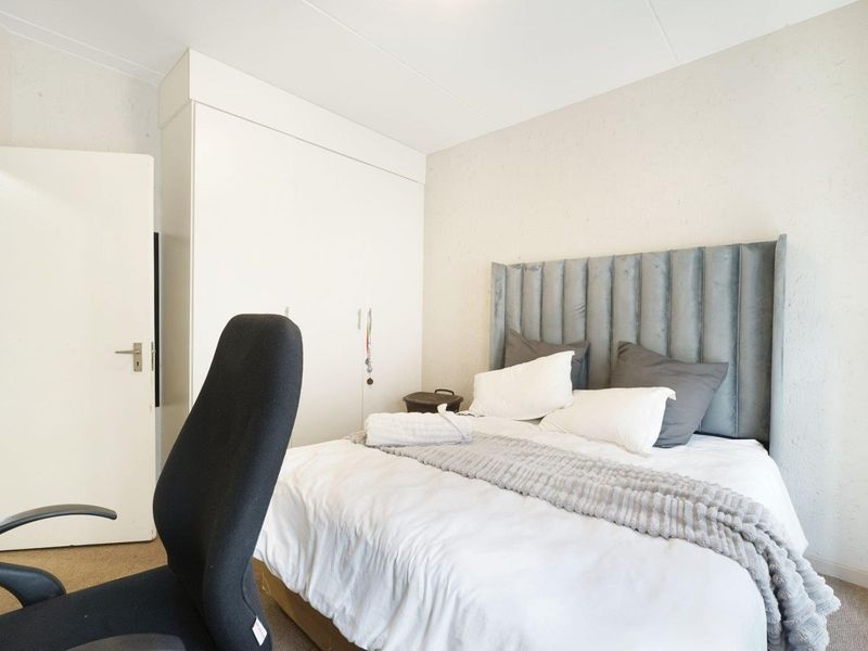 A functional bedroom featuring a built-in wardrobe and neutral wall finishes, providing a comfortable and practical living space.