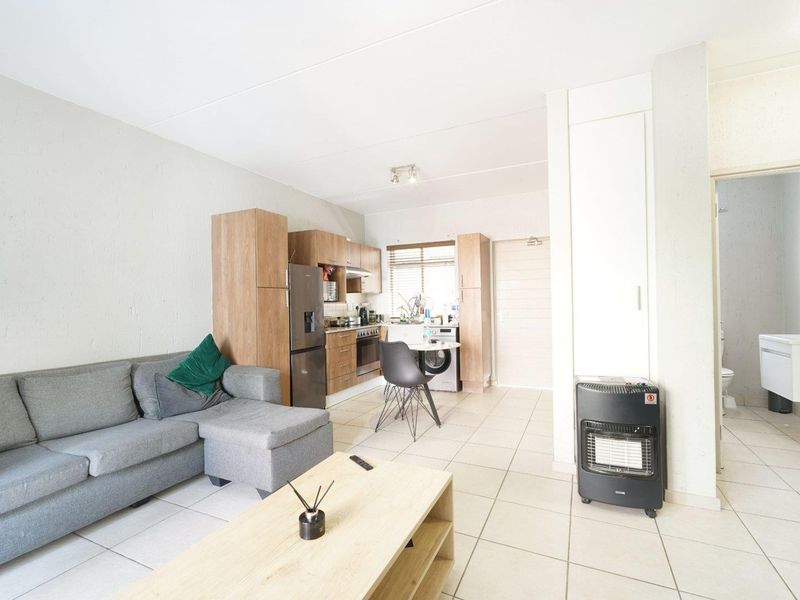 Open-plan living area featuring tiled flooring and a compact kitchen with built-in cabinetry, oven, and extractor fan.