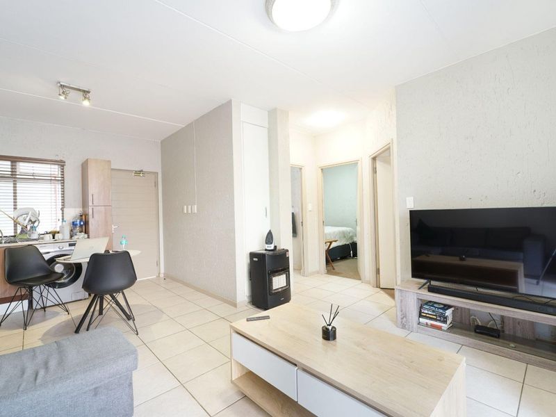 Open-plan living area featuring tiled flooring, integrated kitchen cabinetry, and direct access to adjacent rooms within the apartment.