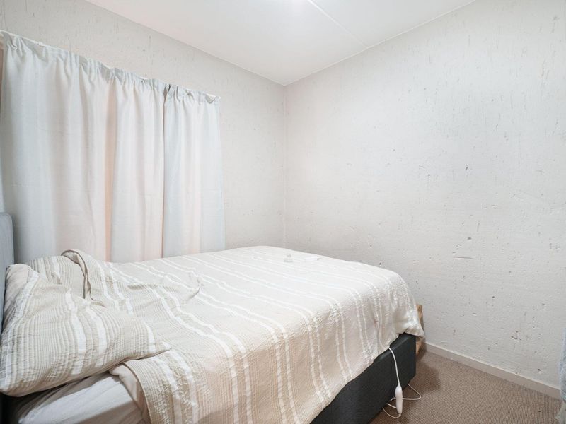 A compact bedroom featuring textured walls and carpeted flooring, offering a neutral base for potential interior updates.