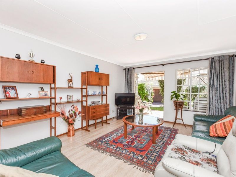 A well-lit living room featuring laminate flooring, coved ceilings, and direct access to the rear garden through a sliding glass door.