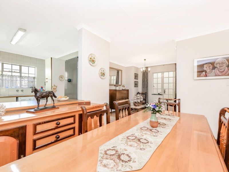 Open plan dining area flowing into a functional kitchen space with built-in cabinetry and tiled finishes.
