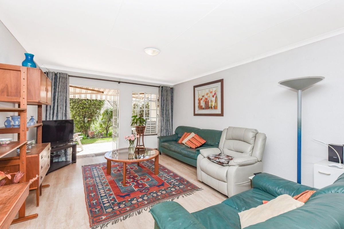 A bright living room featuring laminate flooring and a sliding glass door that provides direct access to the rear garden area.
