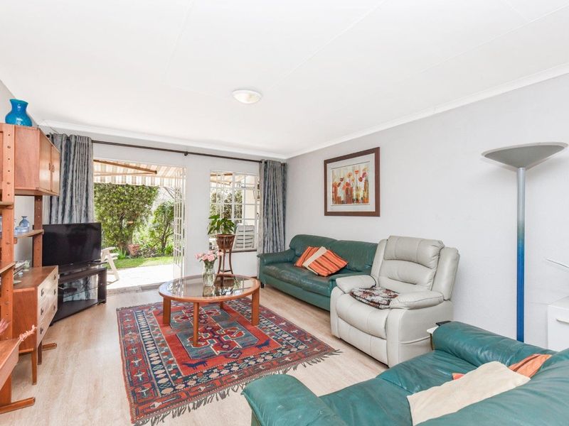 A bright living room featuring laminate flooring and a sliding glass door that provides direct access to the rear garden area.