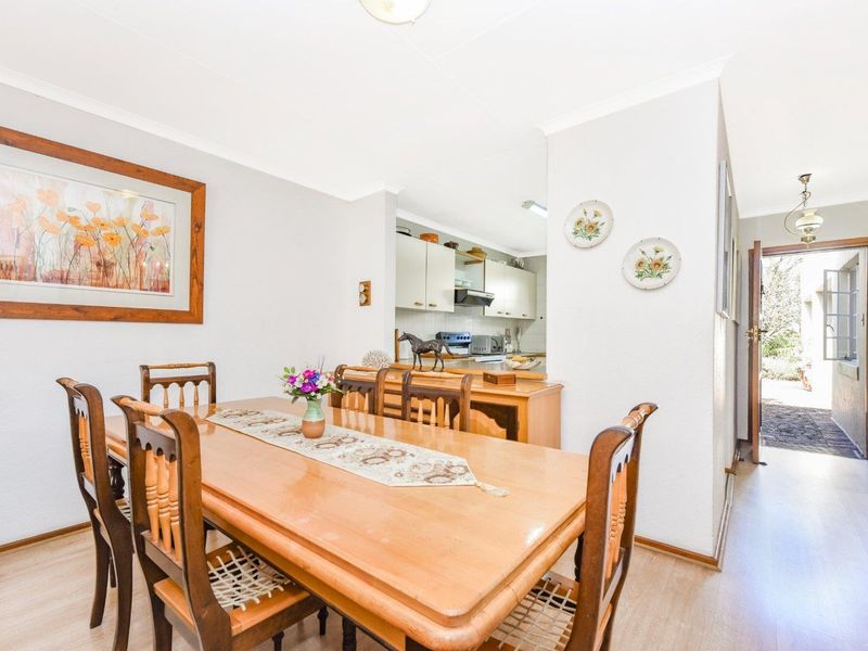 Open plan dining area featuring laminate flooring and coved ceilings, with a direct view into the adjacent kitchen space.