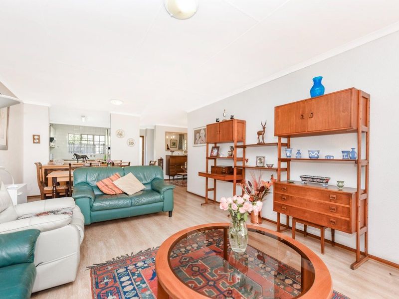 Open plan living and dining area featuring light laminate flooring and neutral walls, with a view through to the kitchen space.