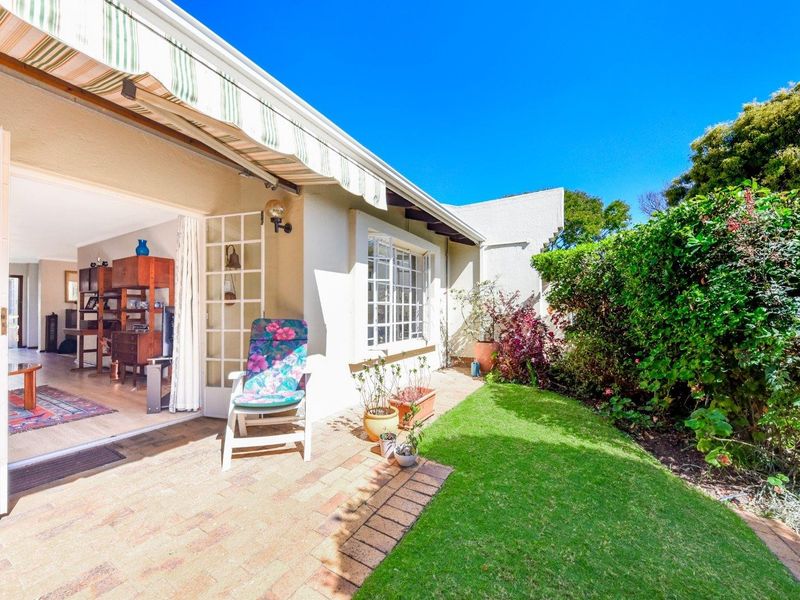 A well-maintained paved patio area featuring a retractable awning, providing seamless indoor-outdoor flow through French doors into the living space.