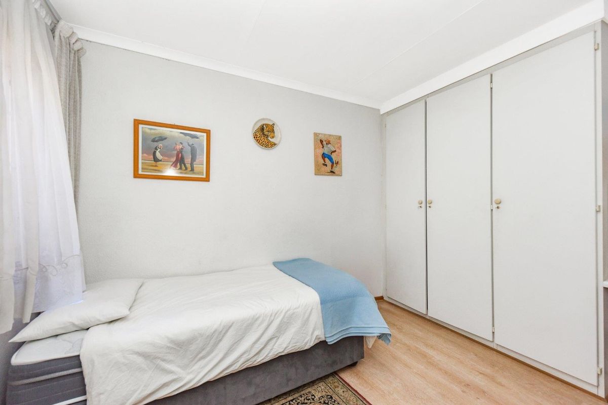 A functional bedroom featuring light laminate flooring, white walls, and built-in cupboards providing ample storage space.