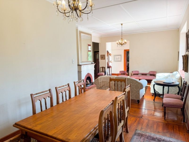 Spacious open-plan living and dining area featuring original hardwood flooring, a classic fireplace with mantelpiece, and traditional ceiling detailing.