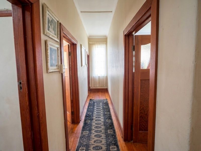 A classic hallway featuring original timber door frames, doors, and polished timber flooring, providing access to multiple rooms within the home.