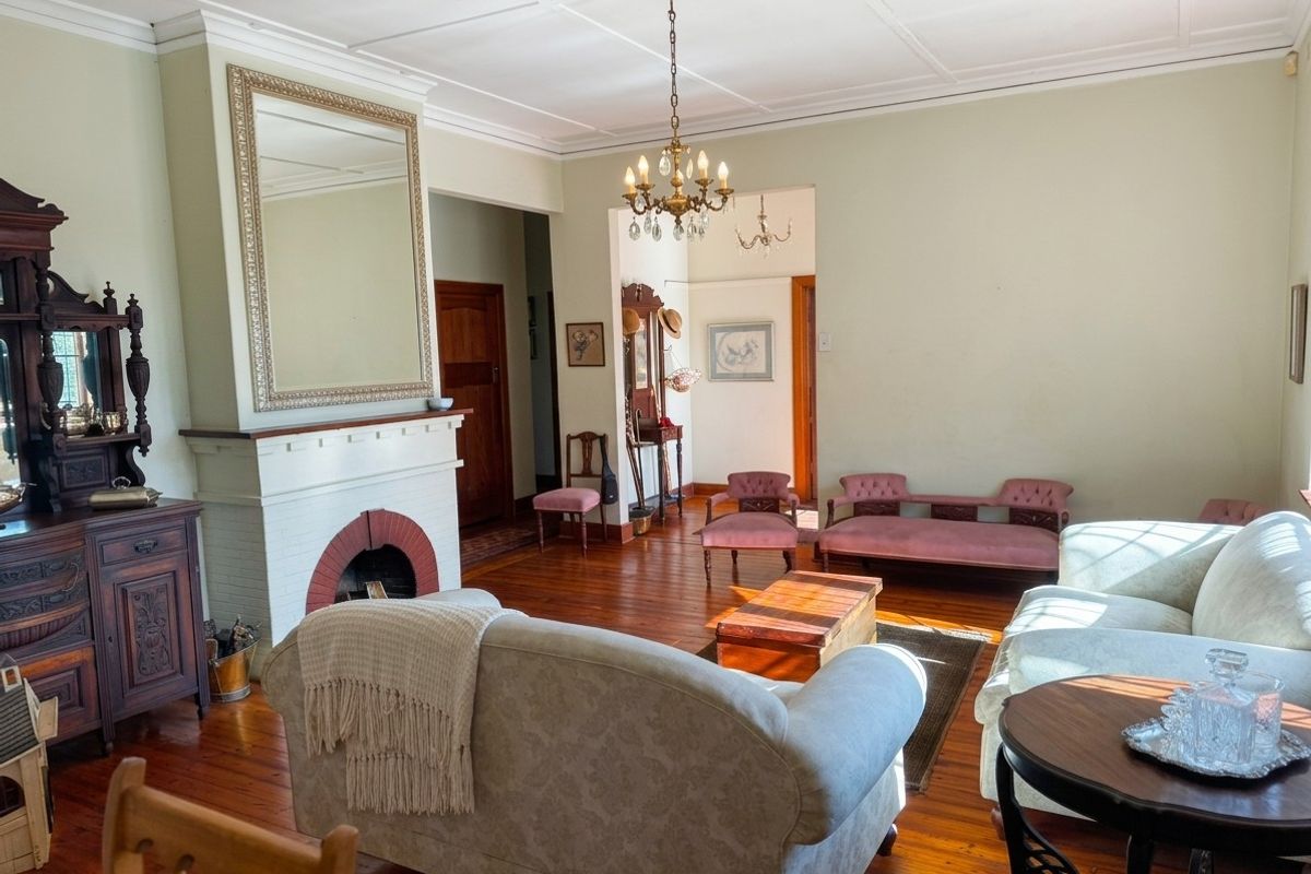 Spacious living room featuring original hardwood flooring, a classic fireplace with a brick hearth, and detailed coffered ceilings.