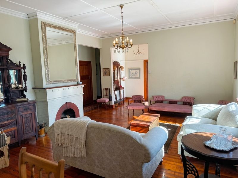 Spacious living room featuring original hardwood flooring, a classic fireplace with a brick hearth, and detailed coffered ceilings.