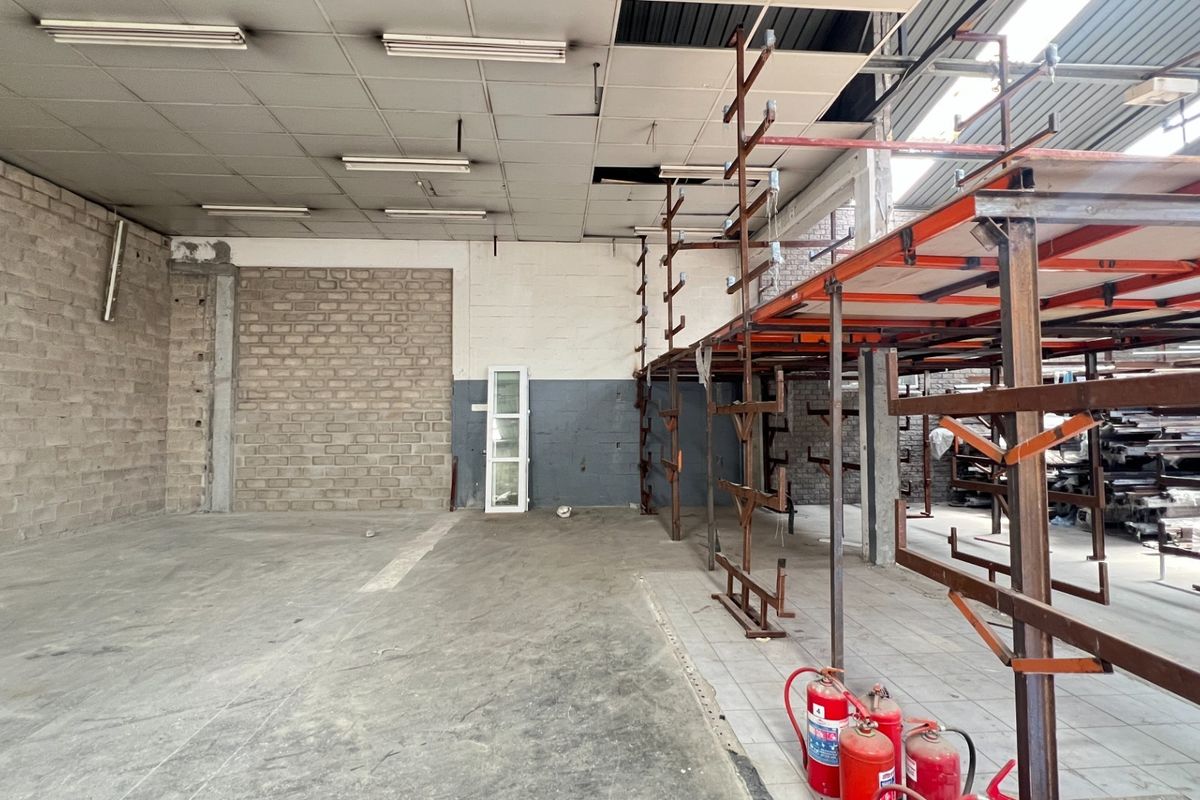 Spacious industrial utility area featuring exposed brick walls, concrete flooring, and integrated steel racking systems, suitable for storage or workshop operations.