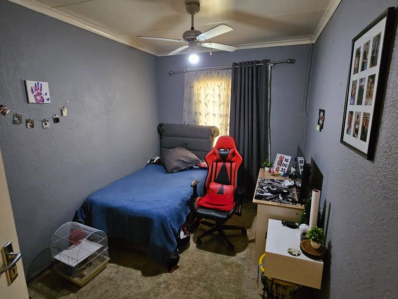 A standard bedroom featuring a ceiling fan and window with curtain rod, providing a functional space for rest or study.
