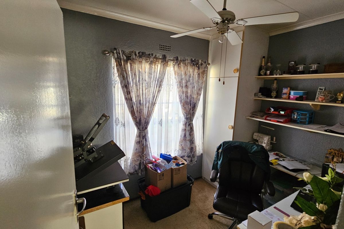 A functional bedroom featuring a ceiling fan, built-in cupboard storage, and wall-mounted shelving units.