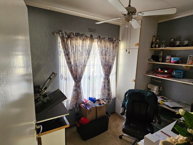 A functional bedroom featuring a ceiling fan, built-in cupboard storage, and wall-mounted shelving units.