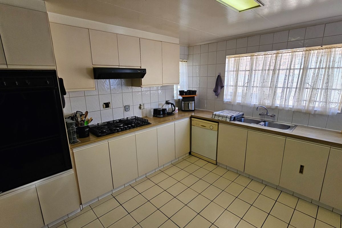 A functional kitchen featuring built-in cabinetry, a gas hob, an integrated oven, and tiled finishes, offering a practical layout with ample counter space.