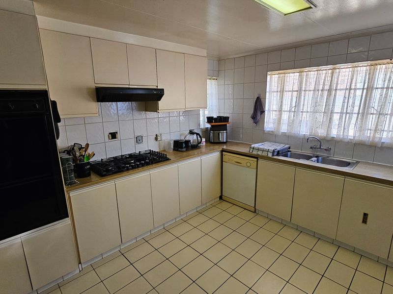 A functional kitchen featuring built-in cabinetry, a gas hob, an integrated oven, and tiled finishes, offering a practical layout with ample counter space.