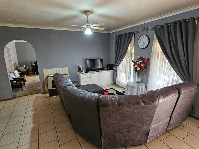 A spacious living room featuring tiled flooring, a ceiling fan, and a distinctive arched doorway leading to an adjacent area.