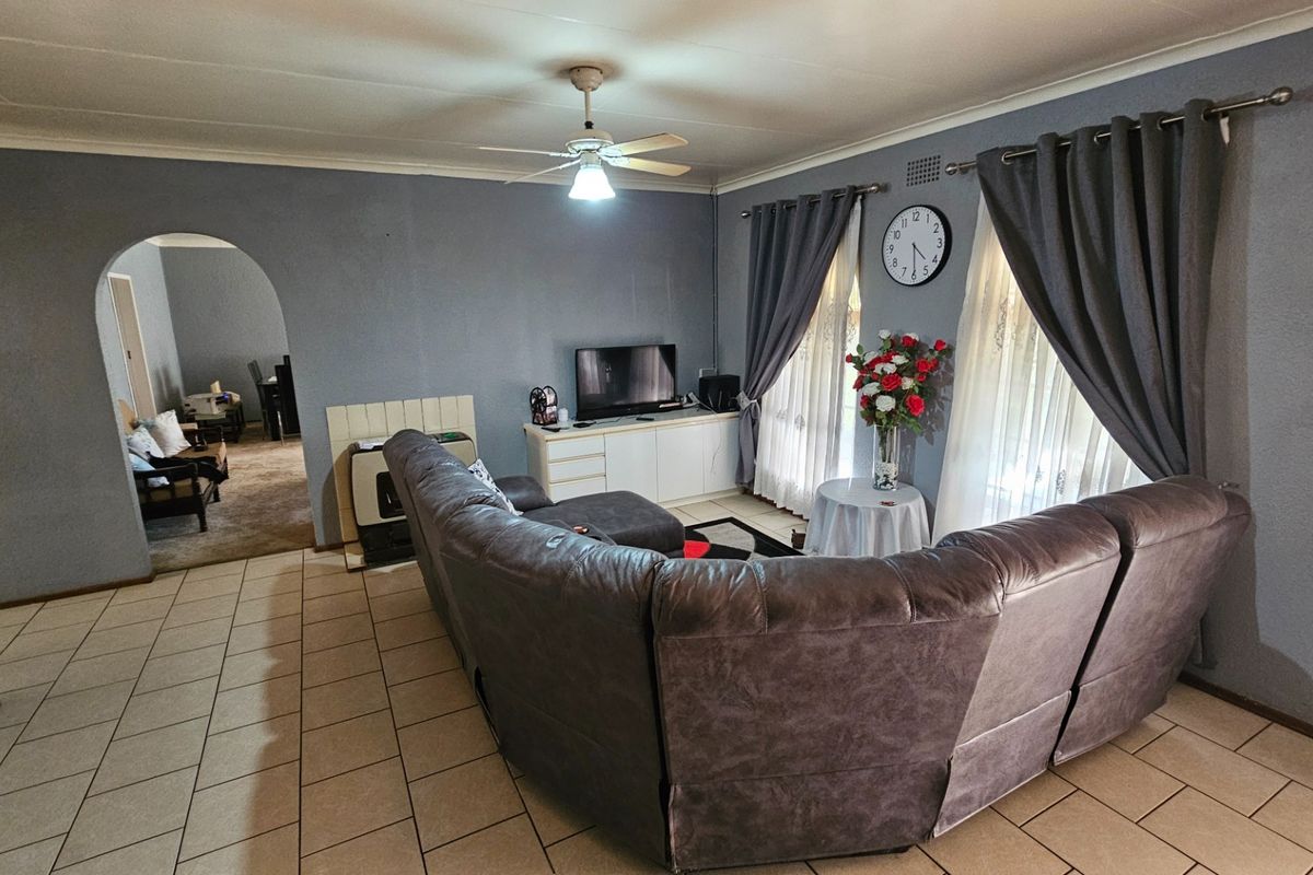 A spacious living room featuring tiled flooring, a ceiling fan, and a distinctive arched doorway leading to an adjacent area.