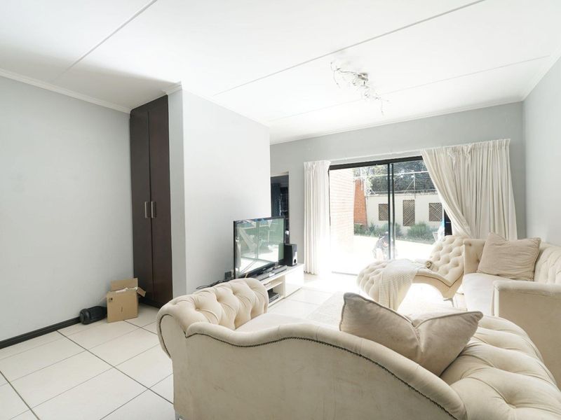 Bright living room featuring tiled flooring, a built-in cupboard, and large sliding glass doors providing access to the exterior.