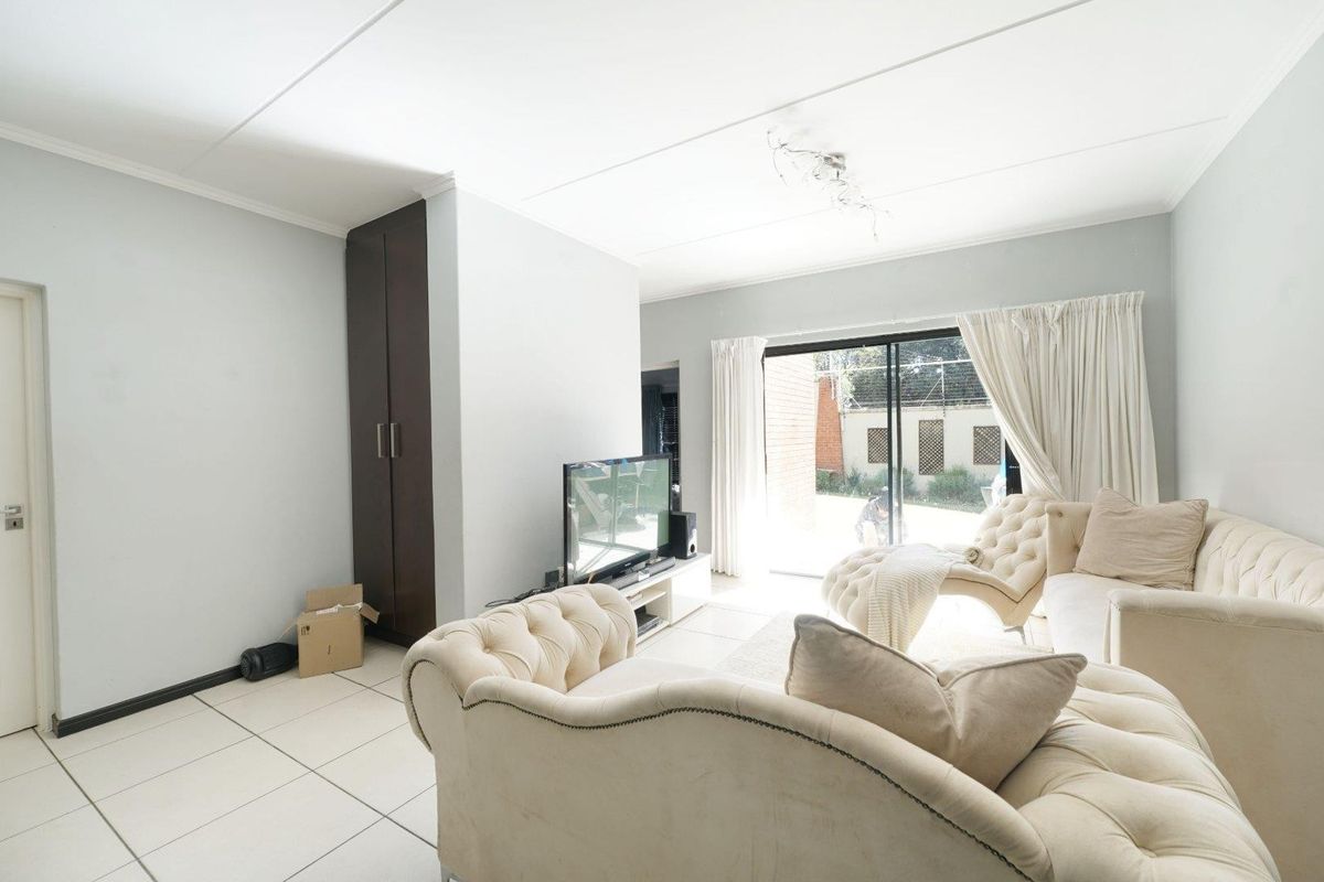 Bright living room featuring tiled flooring, a built-in cupboard, and large sliding glass doors providing access to the exterior.