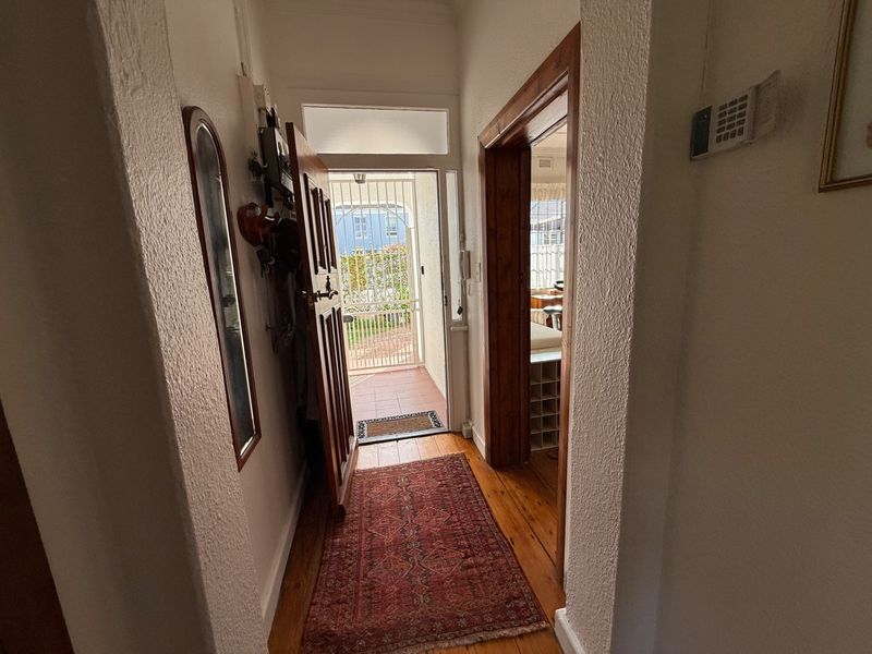 Entrance hallway featuring timber flooring and a secure front door with an external security gate.