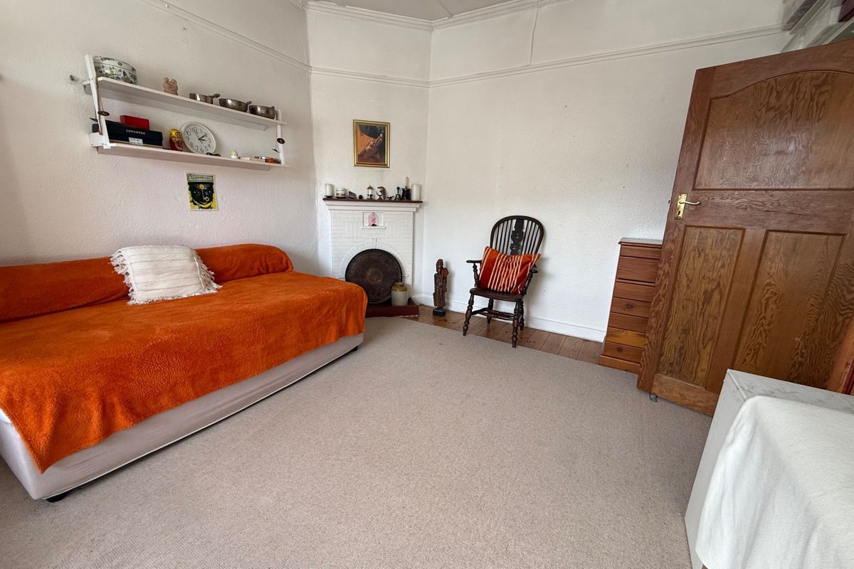 A bedroom featuring a traditional fireplace, picture rails, and original timber door, offering a classic foundation for renovation.