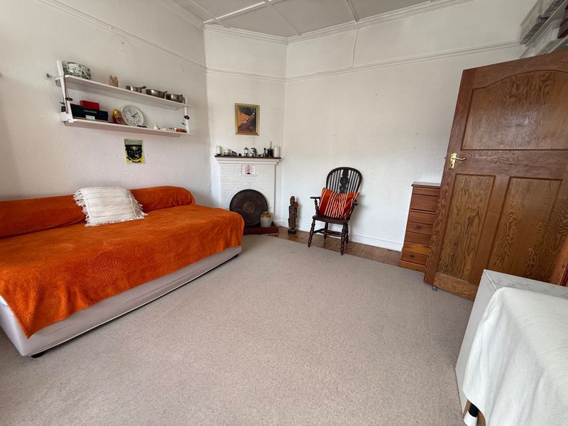 A bedroom featuring a traditional fireplace, picture rails, and original timber door, offering a classic foundation for renovation.