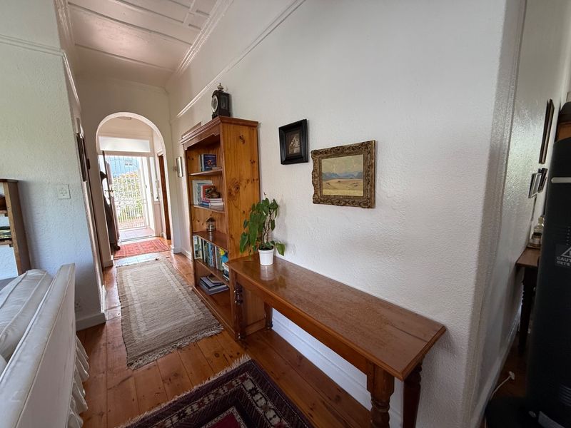 A bright hallway featuring polished timber flooring, a classic archway leading to the entrance, and traditional coved ceiling details.