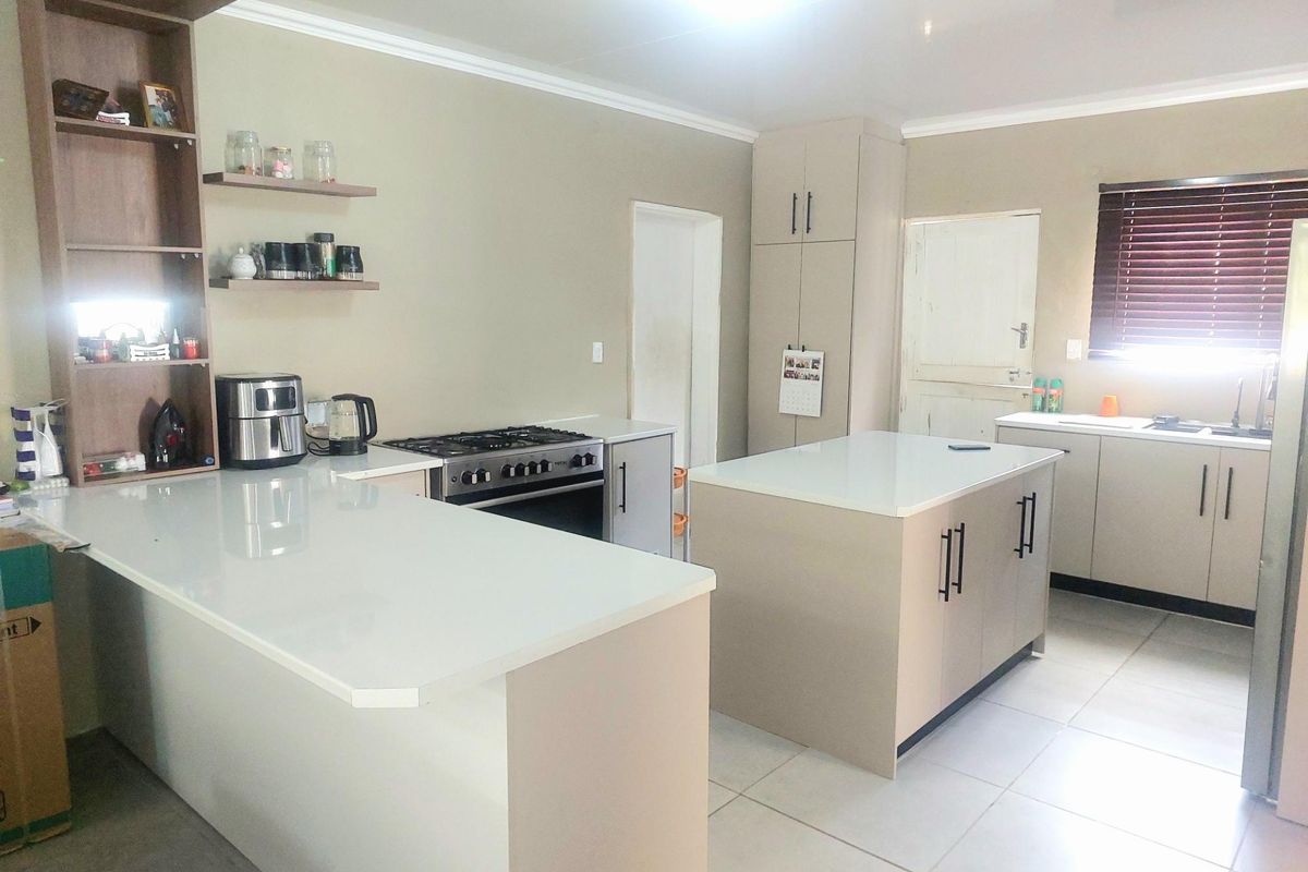 Modern kitchen featuring a central island, quartz countertops, gas stove, oven, and ample built-in cabinetry with neutral finishes.