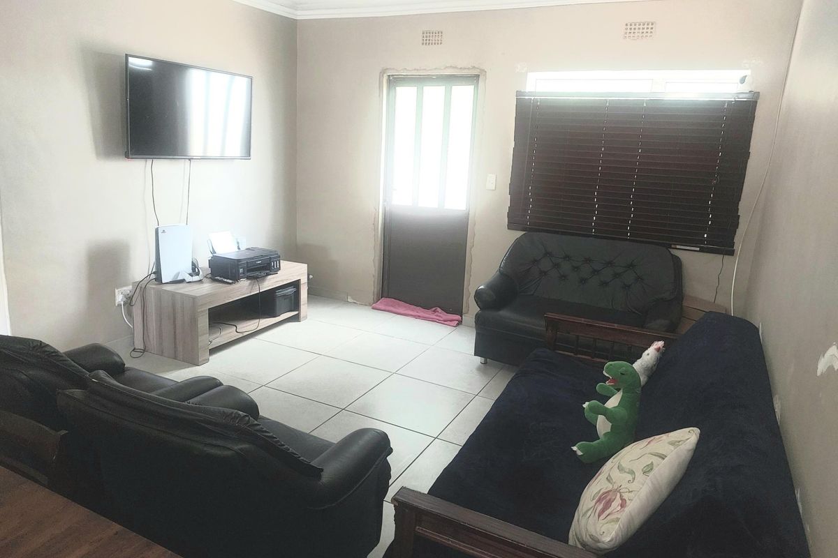A living room featuring tiled flooring, venetian blinds, and an external door, requiring minor cosmetic repairs to wall finishes and door trim.