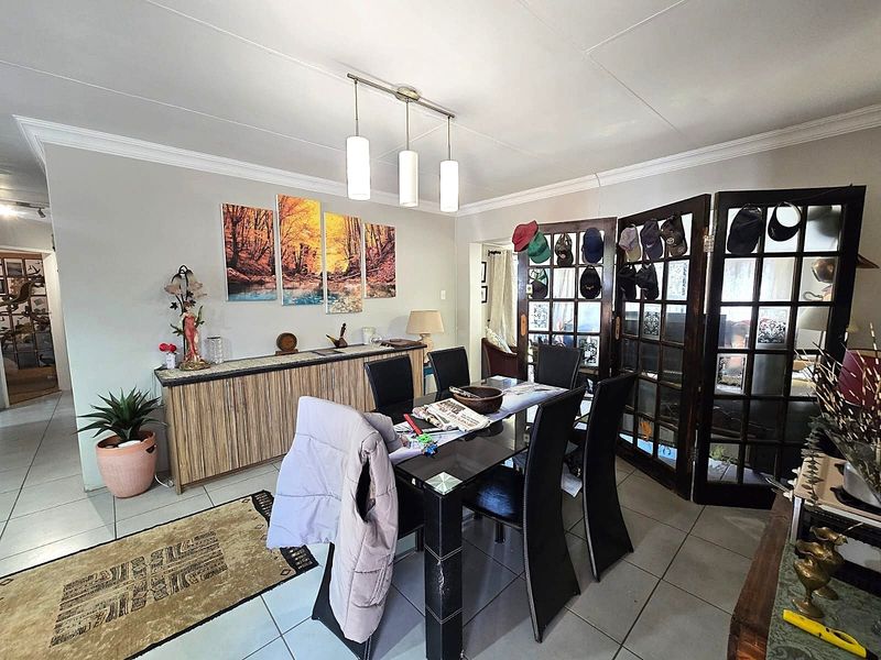 A dining room featuring tiled flooring, crown molding, and decorative french doors, providing a functional space for family meals.