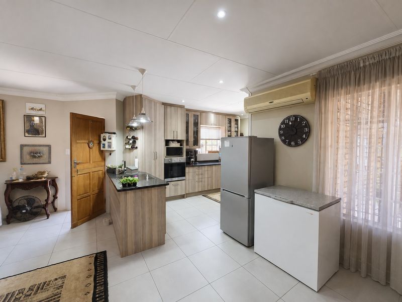 A functional kitchen featuring wood-finish cabinetry, granite countertops, built-in appliances, and tiled flooring, seamlessly integrated into the open-plan living space.