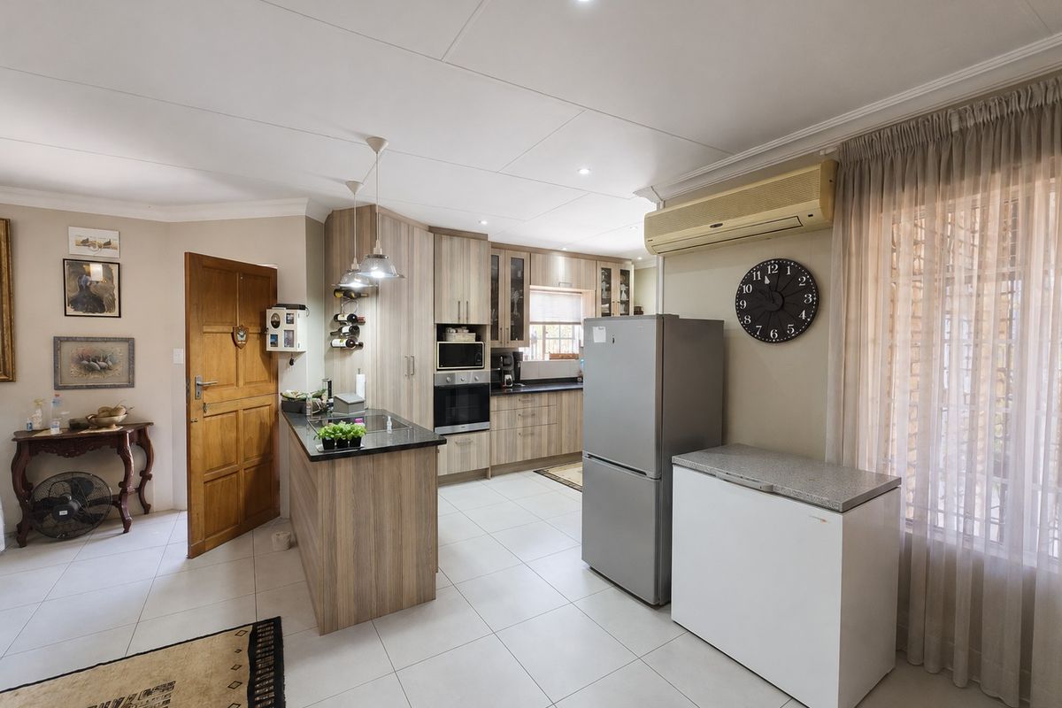 A functional kitchen featuring wood-finish cabinetry, granite countertops, built-in appliances, and tiled flooring, seamlessly integrated into the open-plan living space.