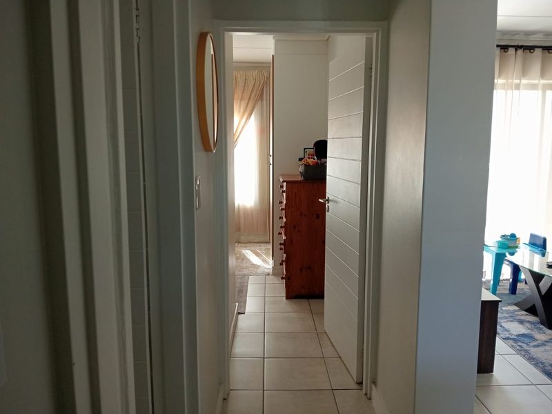 A functional hallway with tiled flooring connecting various rooms within the apartment, providing access to living and bedroom areas.