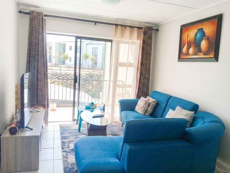 A bright living room featuring tiled floors and a large sliding glass door that provides access to an outdoor balcony area.