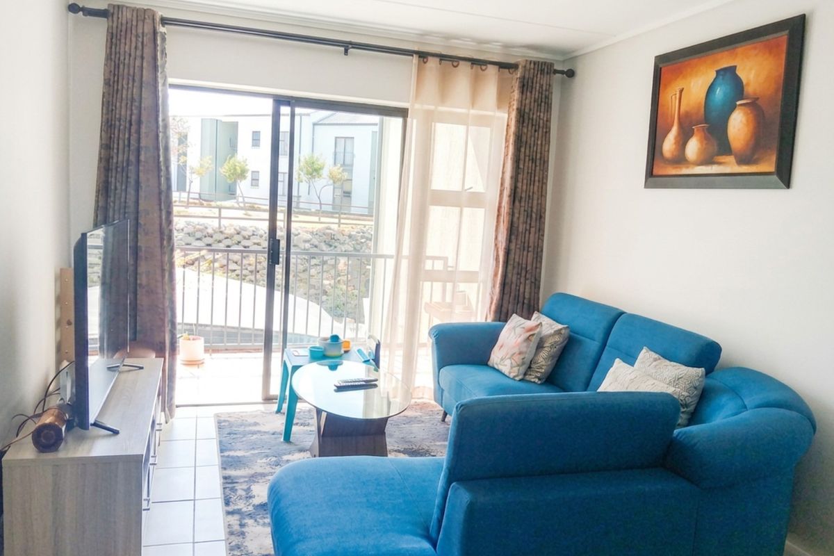 A bright living room featuring tiled floors and a large sliding glass door that provides access to an outdoor balcony area.
